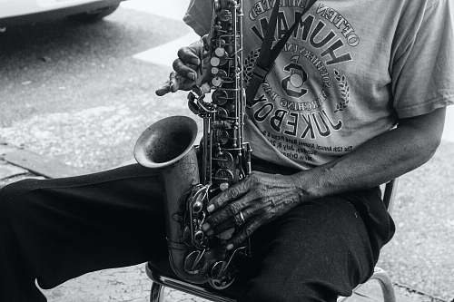 black-and-white grayscale photo of a person playing saxophone while sitting saxophone